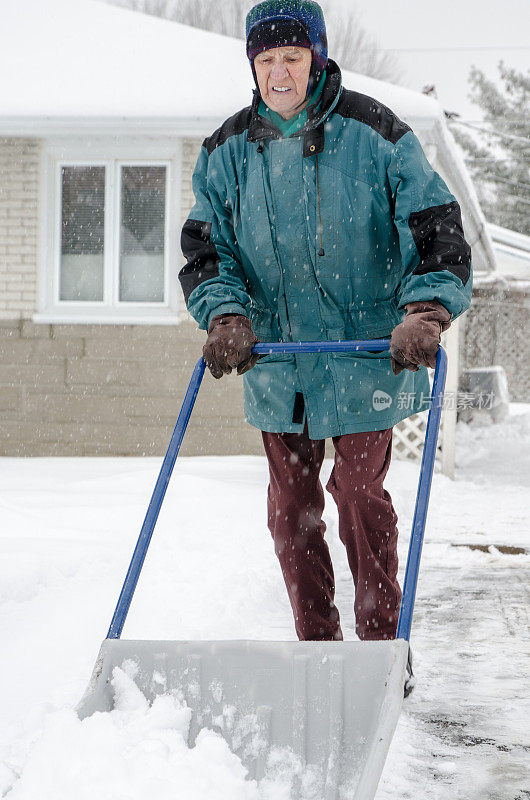 老人在铲车道上的雪