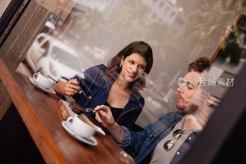 潮人情侣坐在咖啡馆吃布朗尼喝咖啡