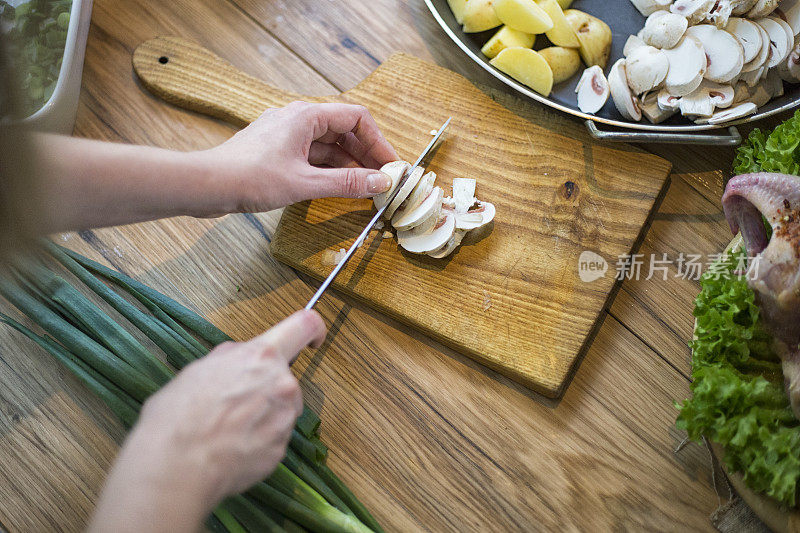 用刀在砧板上切蘑菇的女人。