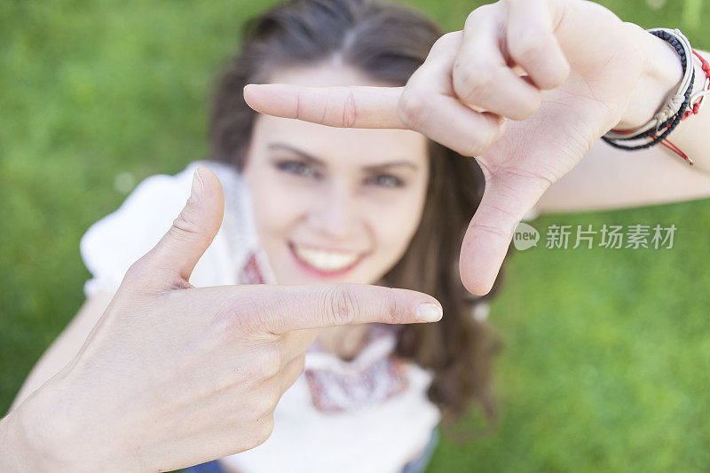 微笑的年轻波西米亚女人做手指框架