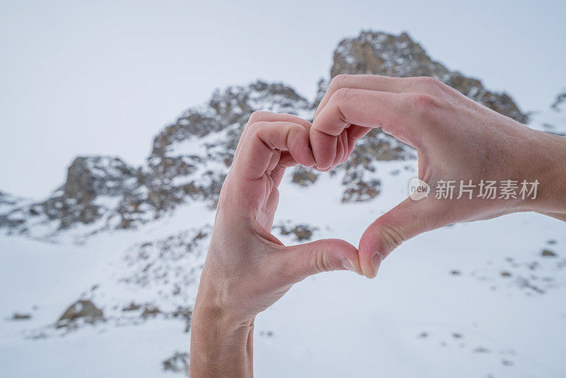 人的双手在雪山景观上做出心形