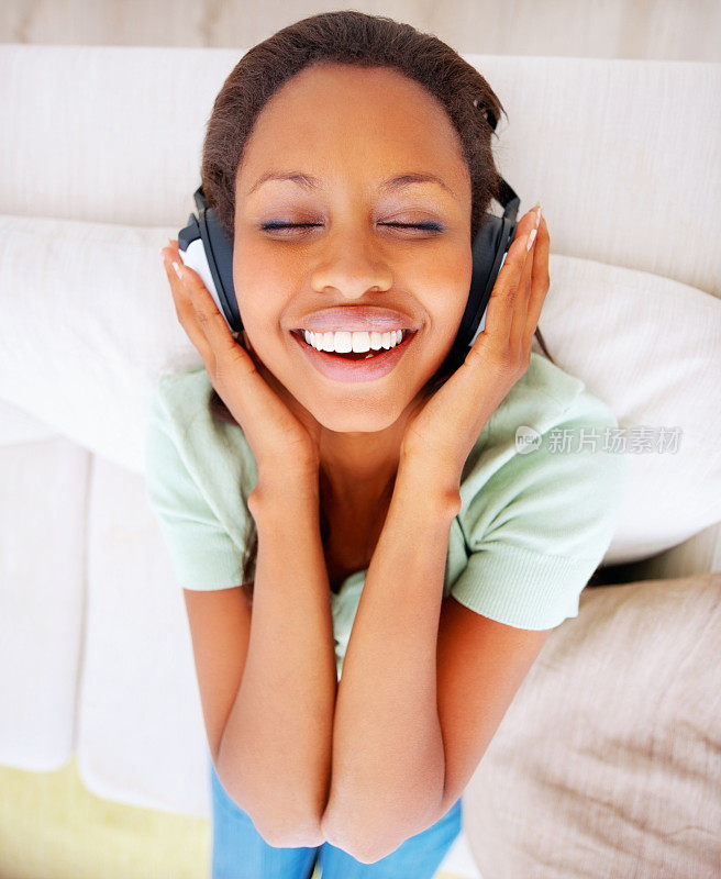 一个年轻女性在耳机上享受音乐的俯视图