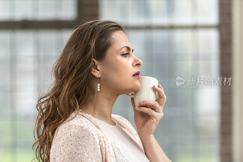 一个站在窗边喝咖啡的女人