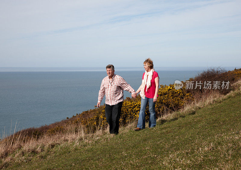 一对成熟的夫妇在海滨小径上享受春天的散步