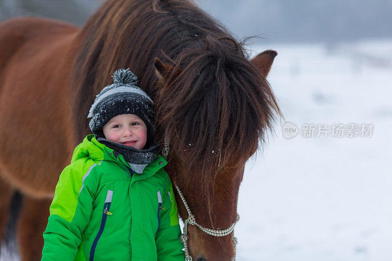 快乐的小男孩和马在雪中