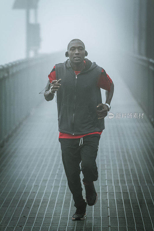 年轻人在铁桥上的雾中奔跑