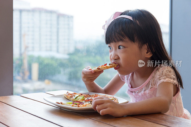 亚洲华人小女孩在吃意大利辣香肠披萨