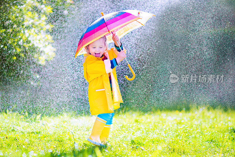 漂亮有趣的小孩拿着伞在雨中玩耍