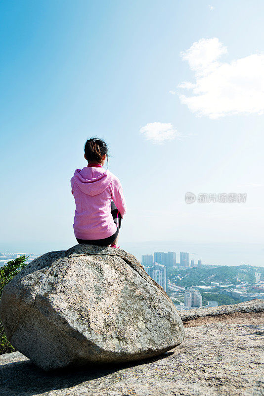 女人坐在山顶的岩石上