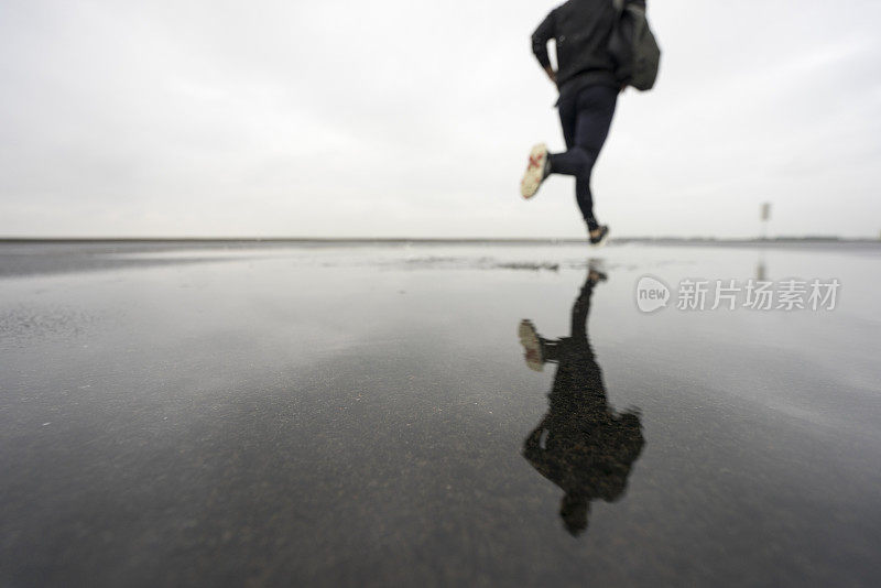 照片中的男运动员跑过水坑对着多云的天空