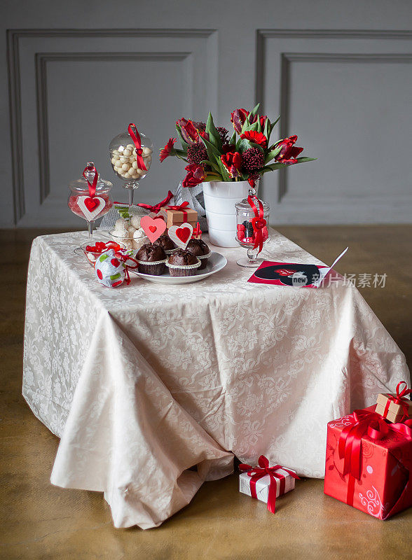 一张用巧克力蛋糕、鲜花和心形装饰的桌子。