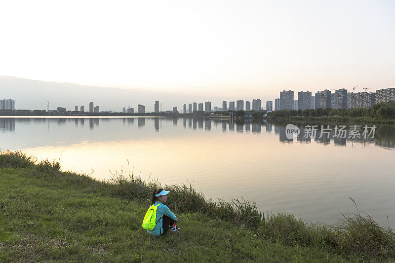 一个年轻女子背着背包坐在湖边的肖像