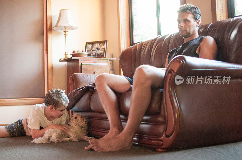 一名男子与儿子和他的宠物马尔济斯坐在客厅里