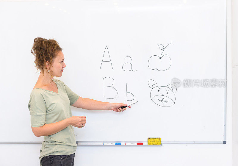 女教师在教室里用白板教字母