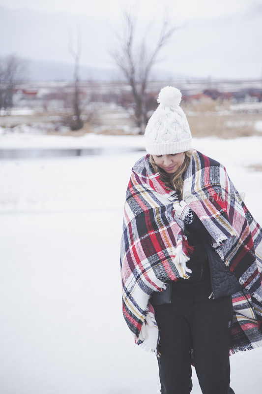 雪地里穿着格子毯子的年轻女子