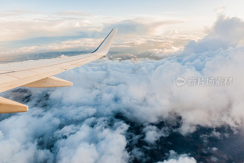 飞机机翼在窗口飞行，多云的天空