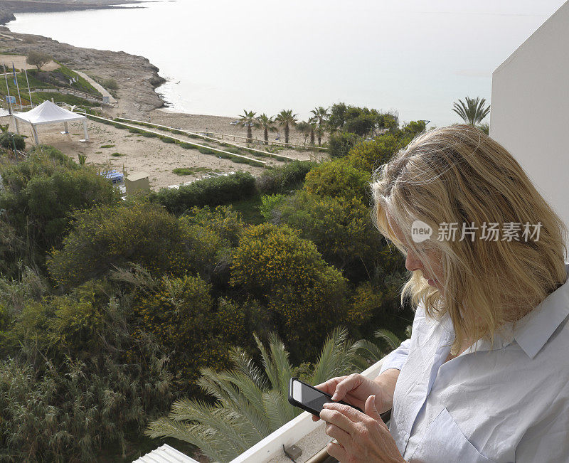 一个女人在海面上的阳台上用手机