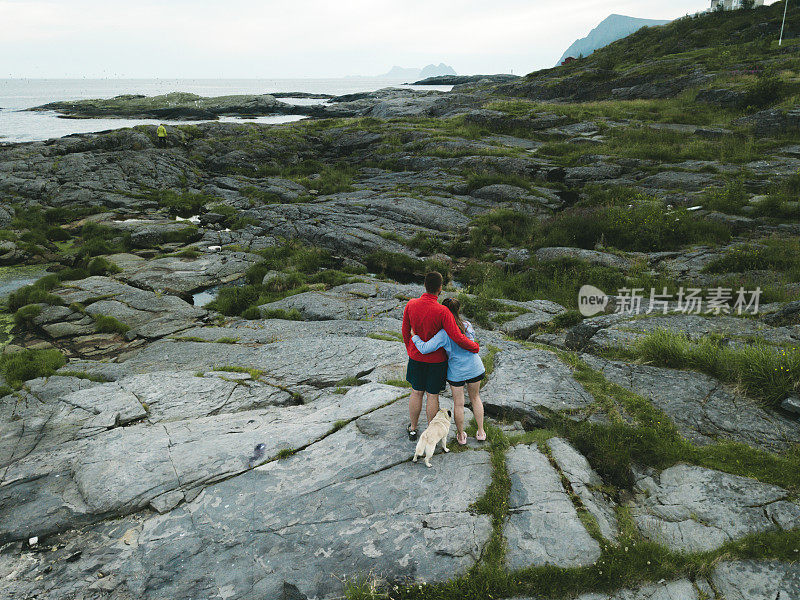 在罗浮敦群岛上，一对夫妇抱着狗看海