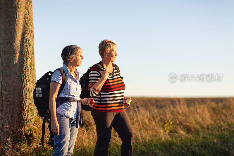 老年妇女徒步旅行休息时喝水