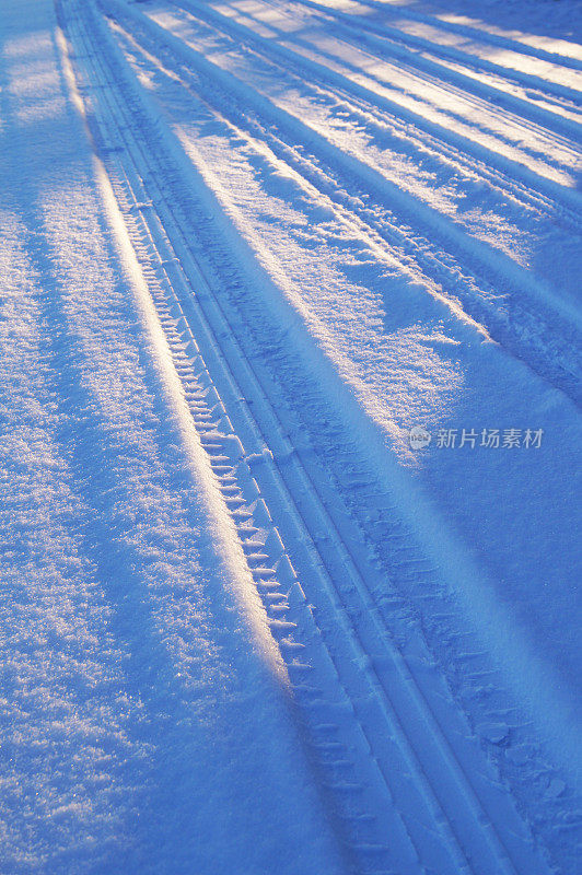 黎明时分雪地上的汽车轮胎印