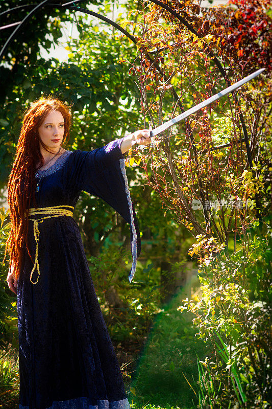 满头红长发的女子在秋天的花园中佩剑。