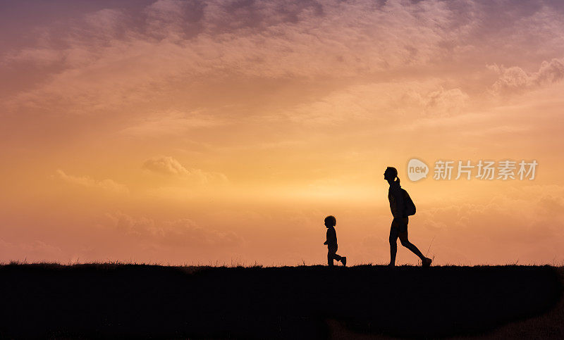 母亲和儿子在夕阳下一起散步。