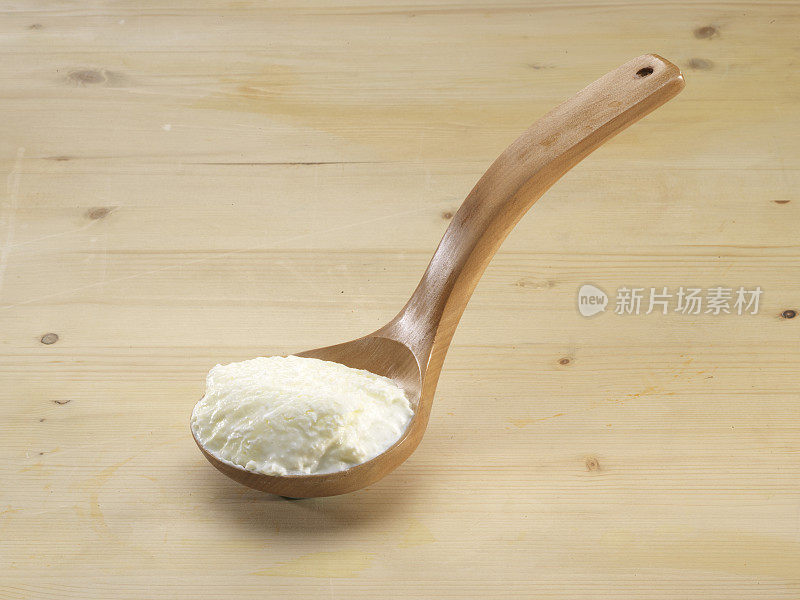一勺白色酸奶放在木头背景上。