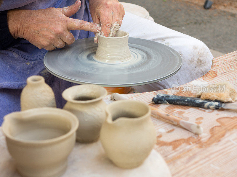 陶工的双手在陶工轮上工作，将粘土制成马克杯
