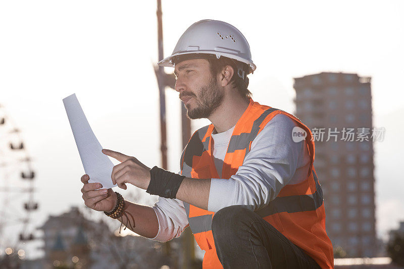 建筑工程师在建筑场地控制数据表和戴安全帽