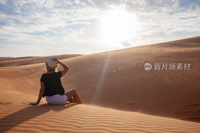 一个女人赤脚站在沙漠的沙丘上