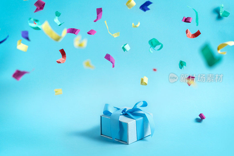 节日快乐!漂亮的蓝色包装的礼物或礼物盒与丝带隔离与明亮的背景复制或空白文字和纸和彩色的五彩纸屑装饰
