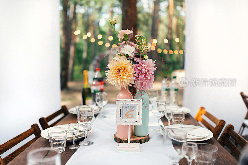 典雅的婚宴餐桌布置，牡丹花饰，酒楼。婚礼表设置。森林婚礼。座位号码。