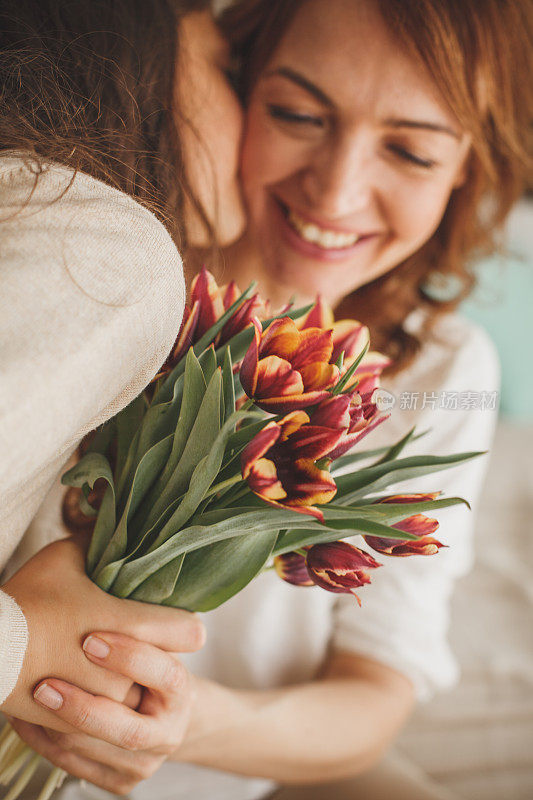 女孩把一束鲜花送给妈妈