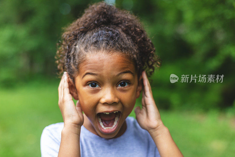 6岁的非洲裔美国华裔女孩摆姿势肖像在郁郁葱葱的户外后院设置