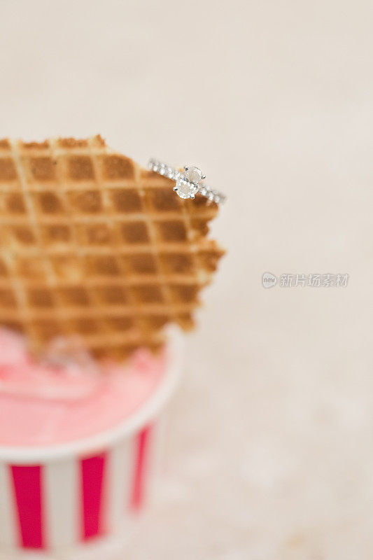 粉色冰淇淋杯上的椭圆形钻石订婚戒指