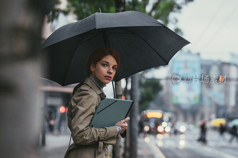 拿着雨伞站在街上的女商人