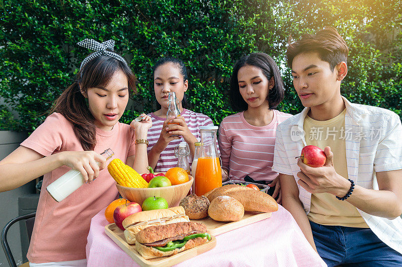 一群快乐的亚洲朋友享受在户外公园野餐，健康的食物和生活理念
