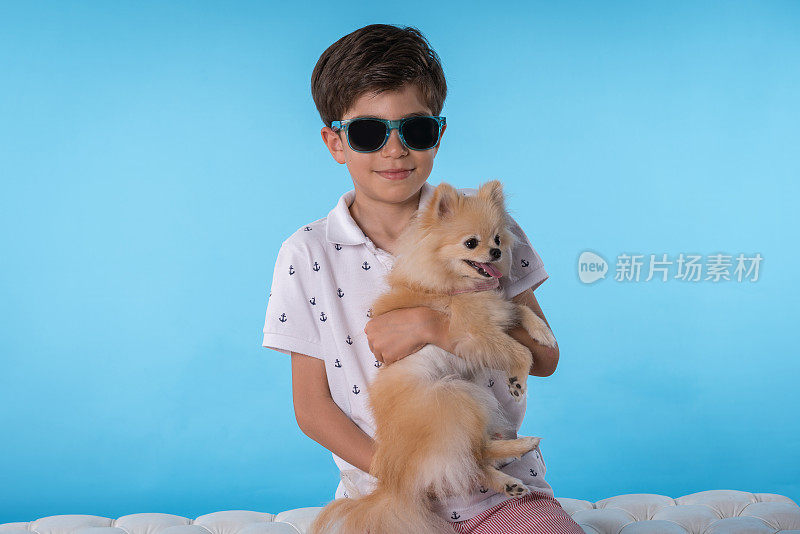 快乐的男孩和她的博美犬坐在怀里