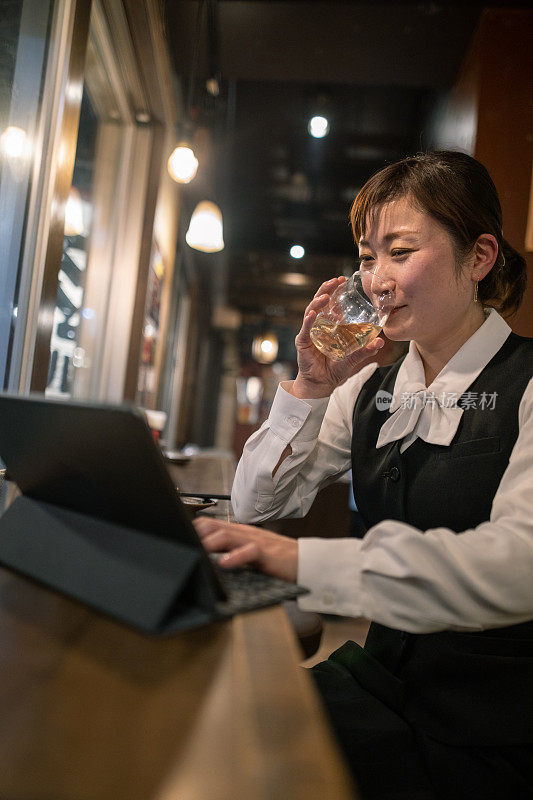 下班后在酒吧用笔记本电脑的女商人