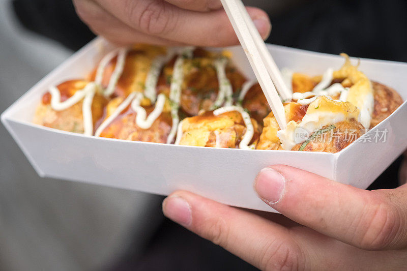 日本街头小吃，男人用筷子吃章鱼丸