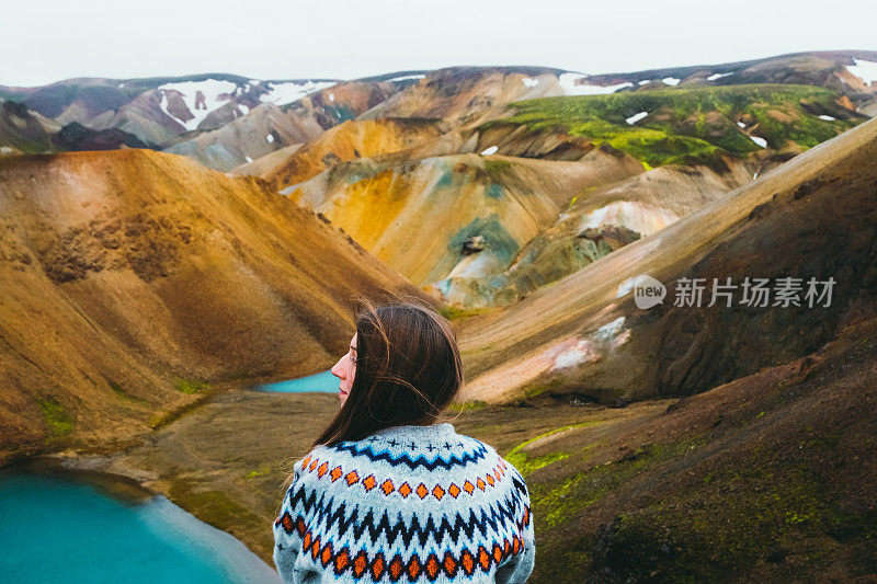 女游客在荒野中欣赏五彩缤纷的彩虹山和绿松石湖