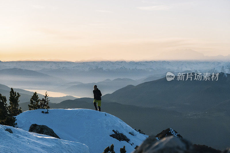 黎明时分，一名徒步运动员爬上雪山的山脊