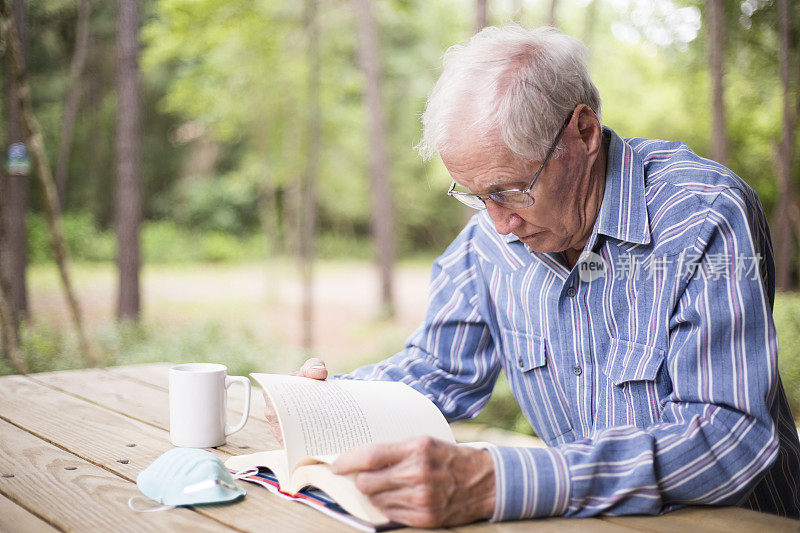 老人在外面看书，桌上放着防毒面具。