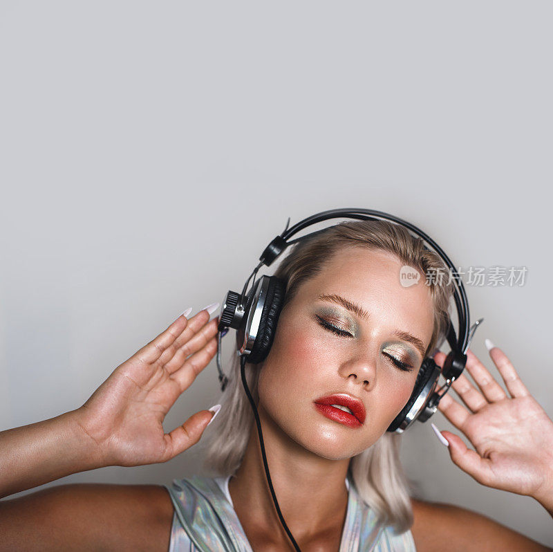 迷人的金发女郎戴着耳机听音乐。