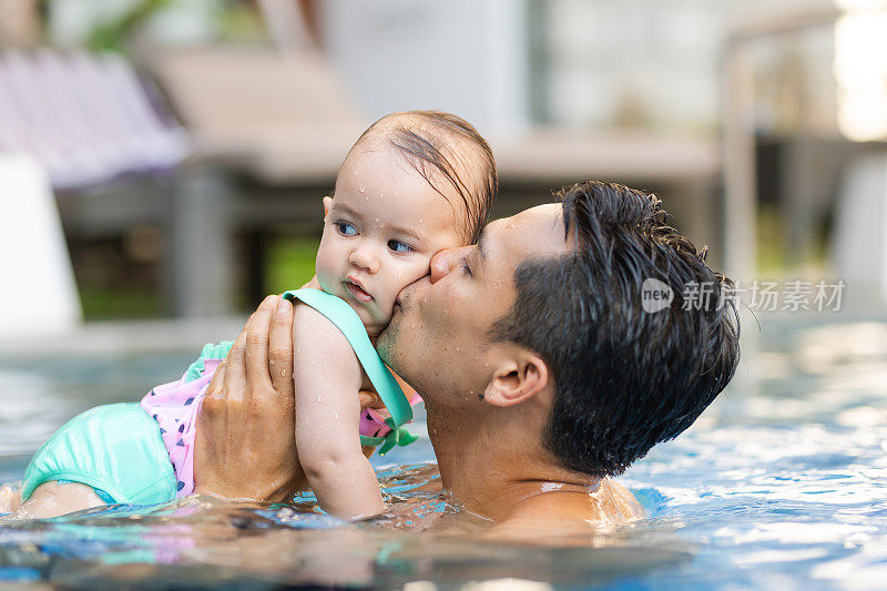 菲律宾爸爸在游泳池里亲吻混血女儿