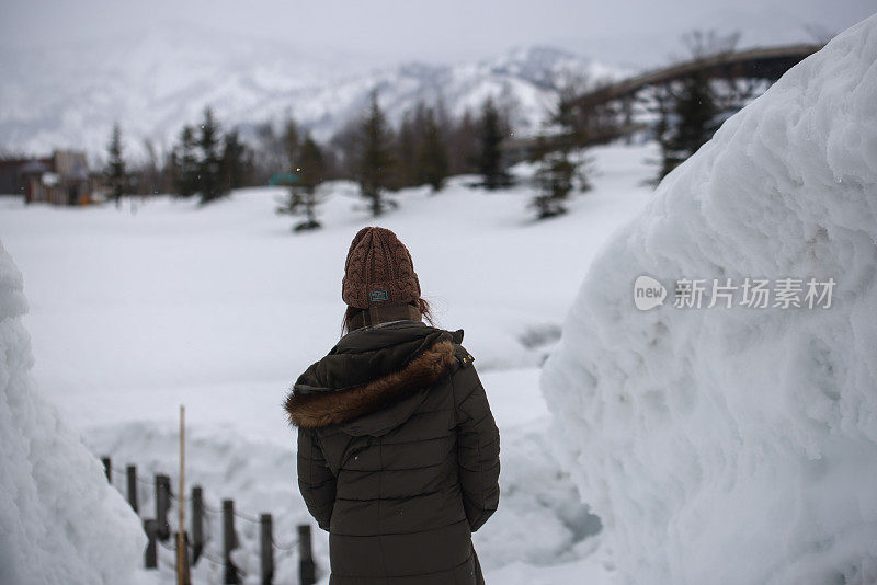 美丽的年轻女子走在雪堆之间的小路上