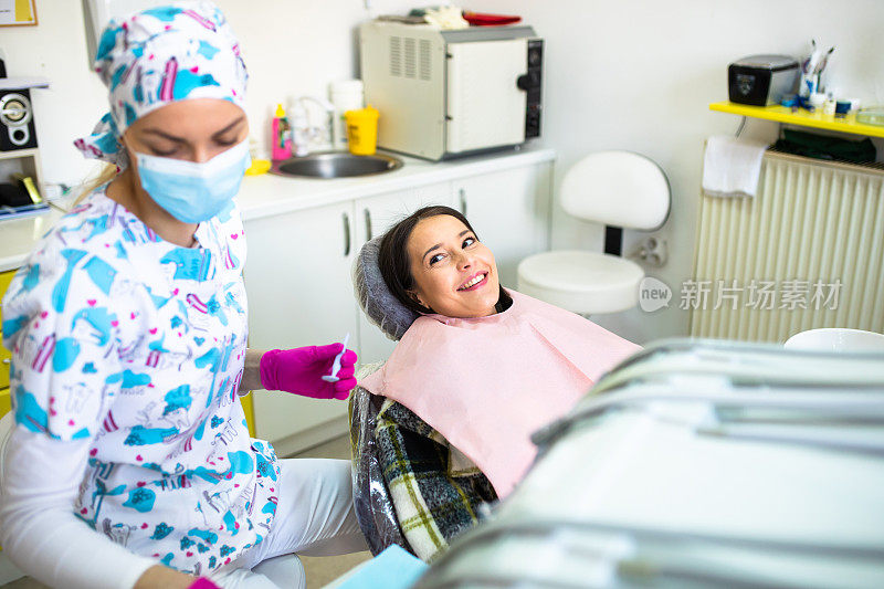 一个坐在牙科椅上微笑的漂亮年轻女人