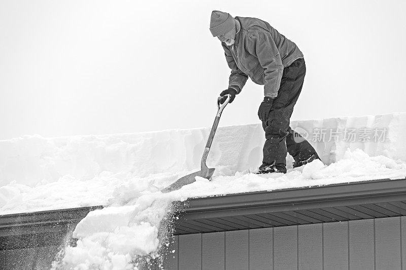 老人从屋顶上铲雪