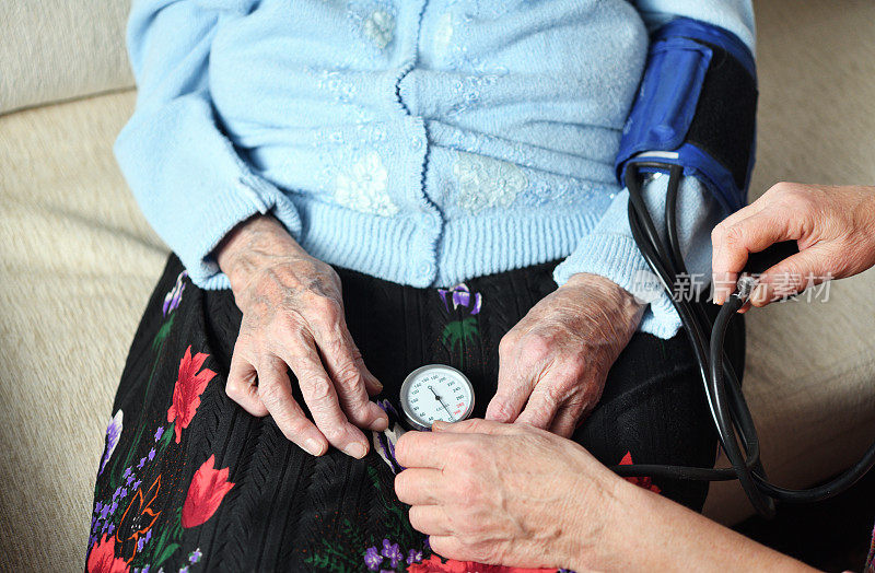 一位医生给一位90岁的女病人量血压。医学健康理念。