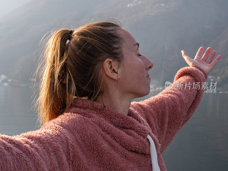 在湖上的码头上，女人张开双臂